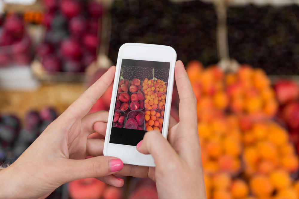 销售购物食品技术和人的概念用智能手机拍照的水果在街边市场上的手的特写